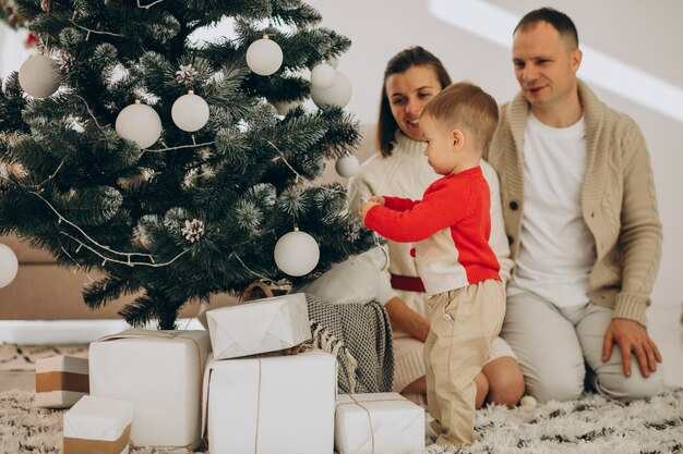 Rodzina z małym synkiem na Boże Narodzenie przy choince w domu