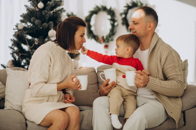 Rodzina z małym synkiem na Boże Narodzenie przy choince w domu