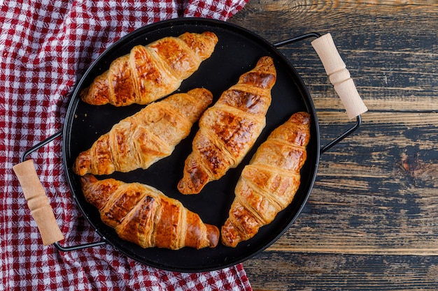 Bezpłatne zdjęcie rogaliki na patelni na ręcznik drewniany i kuchenny. leżał płasko.