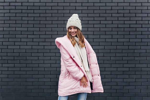 Bezpłatne zdjęcie romantyczna dziewczyna europejska w różowym płaszczu uśmiechnięta w zimny dzień. wesoła jasnowłosa kobieta bawi się podczas zimowej sesji zdjęciowej.