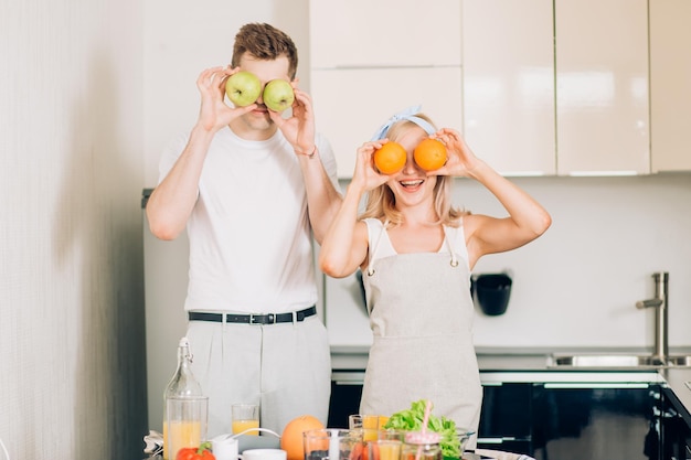 Romantyczna para nowożeńców, gotowanie zdrowej żywności i wspólna zabawa w kuchni w domu. kaukaski kobieta i mężczyzna przygotowuje sałatkę jarzynową i koktajl owocowy.