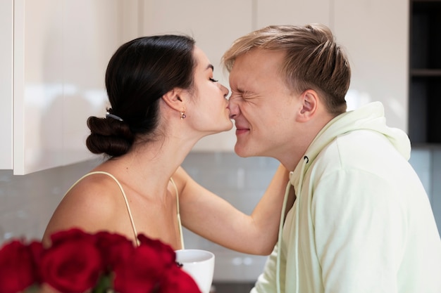 Bezpłatne zdjęcie romantyczna para w domu świętująca walentynki z bukietem pięknych czerwonych róż