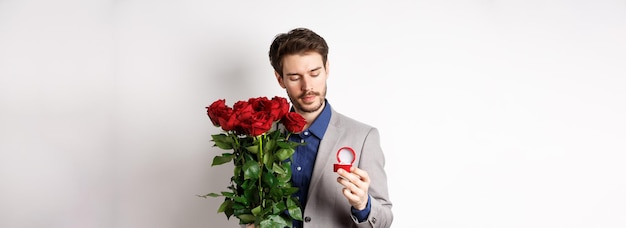 Bezpłatne zdjęcie romantyczny mężczyzna w garniturze, patrzący zamyślony na pierścionek zaręczynowy, zamierzający złożyć propozycję małżeństwa na valenti
