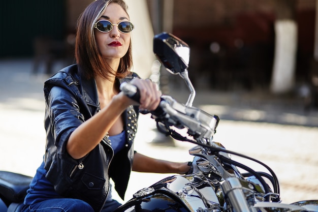 Rowerzysta dziewczyna w skórzanej kurtce na motocyklu