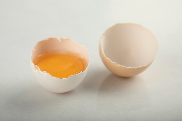 Rozbite jajko organiczne na białej powierzchni.