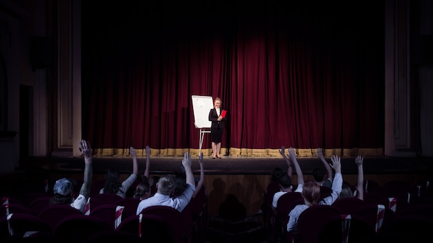 Rozmowa Ze Studentami. Kobieta Mówca Dając Prezentację W Hali W Warsztatach. Centrum Biznesowe. Widok Z Tyłu Uczestników Na Widowni. Impreza Konferencyjna, Szkolenie.