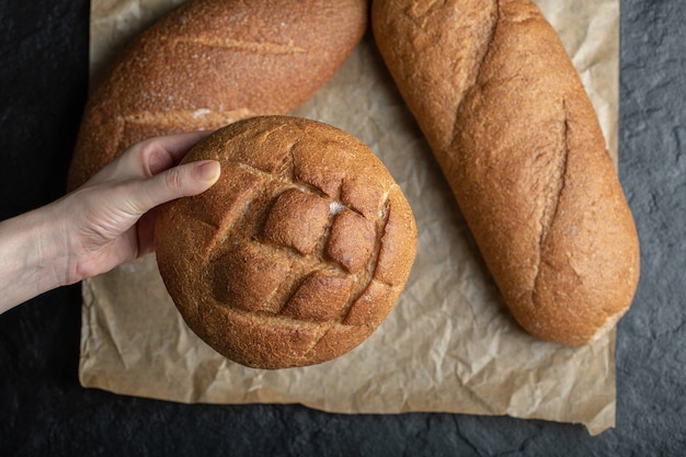 Różne bochenki chleba. Kobieta trzyma ręką.