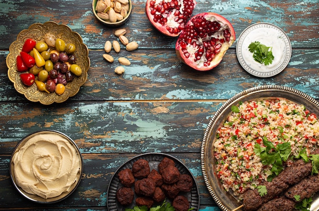 Różne dania kuchni tureckiej: kebab mięsny z sałatką tabbouleh, falafel, hummus, oliwki, pistacje i meze z bliskiego wschodu na drewnianym stole z miejscem na kopię. etniczne arabskie jedzenie, kuchnia turecka