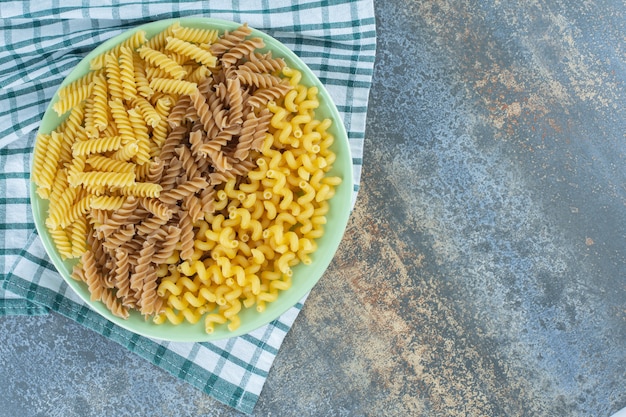 Różne Makarony W Misce Na Ręczniku, Na Marmurowym Tle.