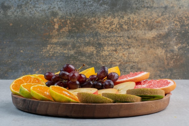 Bezpłatne zdjęcie różne plastry owoców na drewnianym talerzu. zdjęcie wysokiej jakości