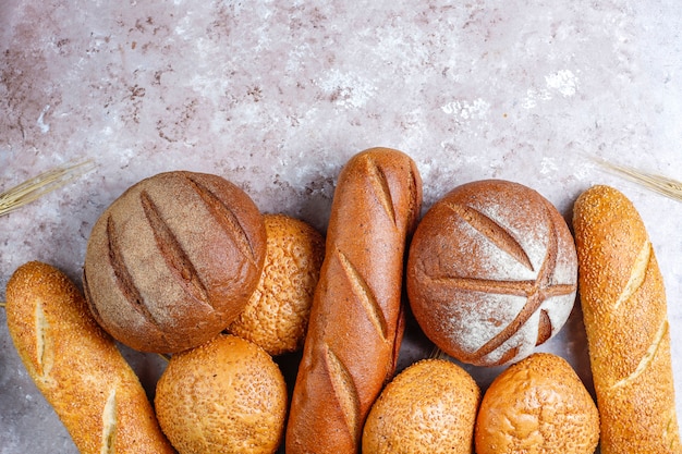 Różne rodzaje świeżego chleba jako tło, widok z góry