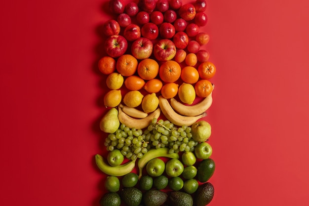 Bezpłatne zdjęcie różne zdrowe owoce cytrusowe na jasnoczerwonym tle. dojrzałe brzoskwinie, jabłka, pomarańcze, banany, winogrona i awokado dla zdrowego odżywiania. zestaw pożywnych potraw. zbilansowana dieta, czyste odżywianie.