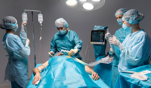 Różni lekarze wykonujący zabieg chirurgiczny na pacjencie
