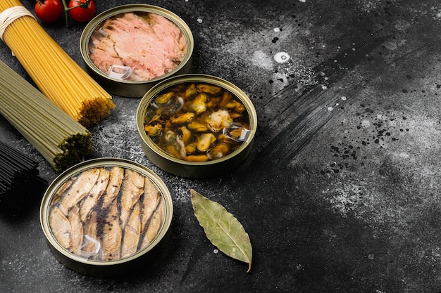 Różnorodność puszek z tuńczykiem z małży i owoców morza ustawionych na czarnym tle ciemnego kamiennego stołu, z miejscem na kopię dla tekstu