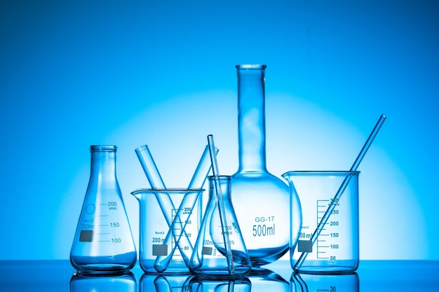 Różnorodność szklanych kolb i sprzętu laboratoryjnego na niebieskim tle