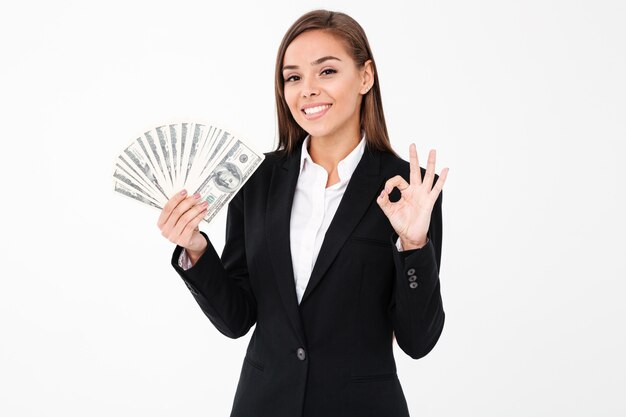 Rozochocona biznesowa kobieta pokazuje zadowalającego gesta mienia pieniądze