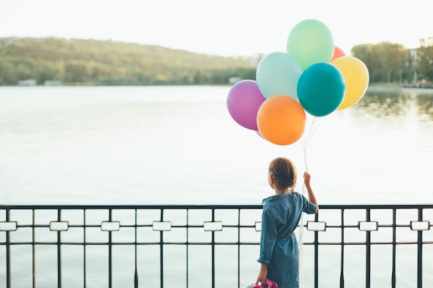 Rozochocona Dziewczyna Trzyma Kolorowych Balony I Dziecięcą Walizkę