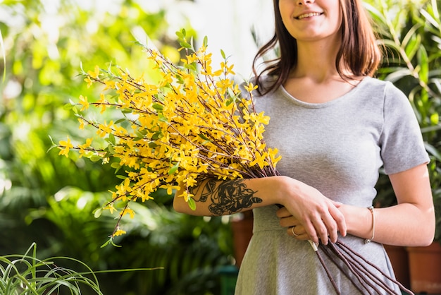Bezpłatne zdjęcie rozochocona kobieta trzyma wiązkę rośliny gałązki