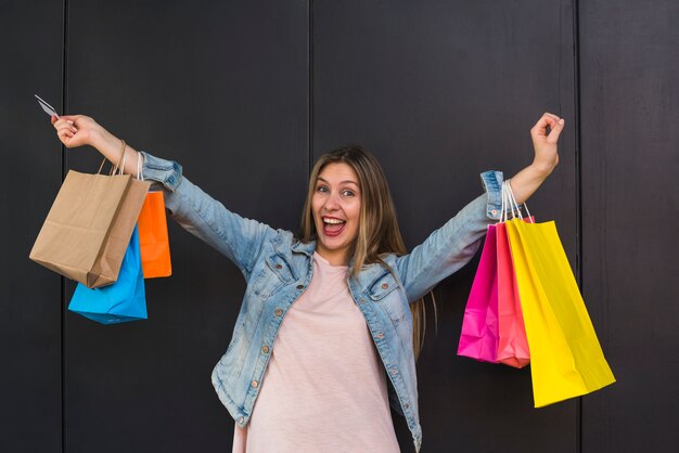 Rozochocona kobiety pozycja z kolorowymi torba na zakupy