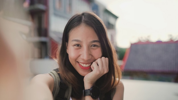 Rozochocona piękna Młoda Azjatycka backpacker blogger kobieta używa smartphone bierze selfie