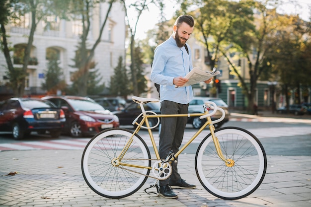 Rozochoconego mężczyzna czytelniczy gazetowy pobliski rower