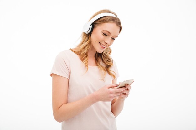 Rozochoconej młodej damy słuchająca muzyka używać telefon komórkowego.