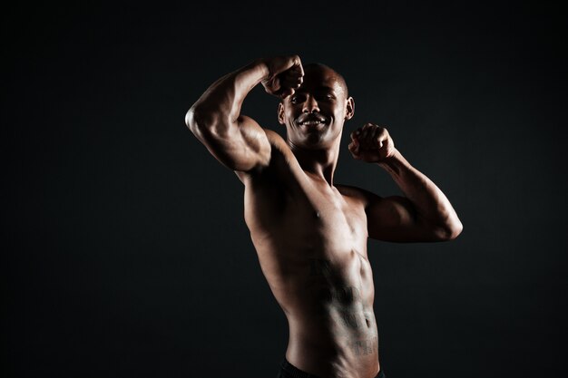 Rozochocony afro amerykański sporta mężczyzna pokazuje jego bicepsy