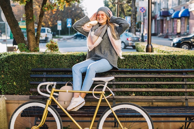 Bezpłatne zdjęcie rozochocony kobiety obsiadanie na ławce blisko bicyklu