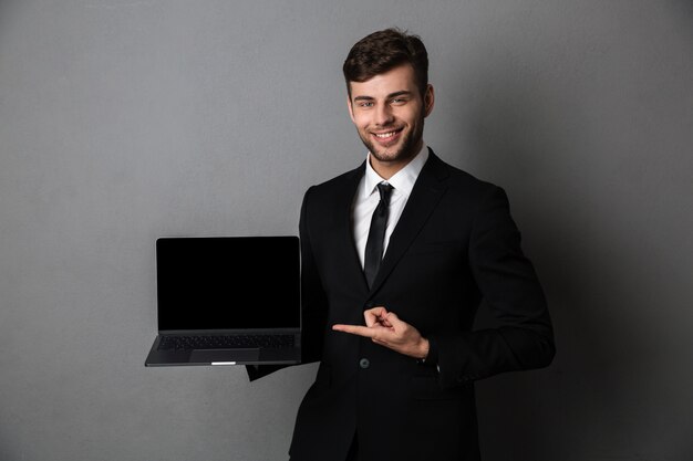 Rozochocony młody biznesowy mężczyzna seansu pokaz laptop