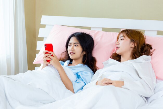 Rozochocony nastolatek kobiety use smartphone selfie na łóżku