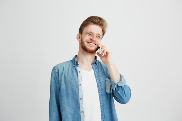 Rozochocony szczęśliwy młody człowiek śmia się uśmiecha się opowiadający na telefonie.