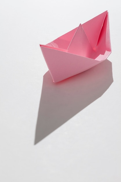 Różowa papierowa łódź na białym tle