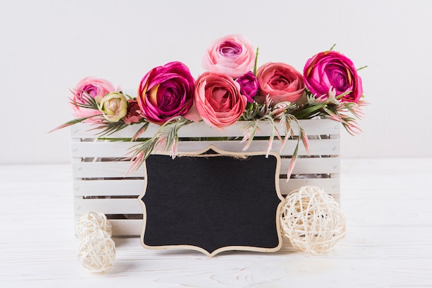 Bezpłatne zdjęcie różowa róża kwiaty z małym tablicy na stole