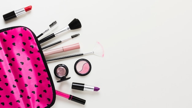 Bezpłatne zdjęcie różowy futerał do makijażu z kosmetykami i pędzlami