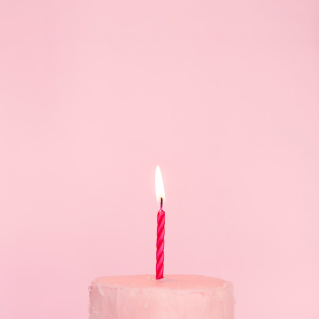 Różowy tort z zapaloną świecą