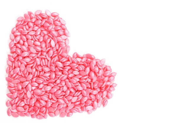 Różowy wosk do depilacji w granulkach, w kształcie serca na izolowanym białym tle