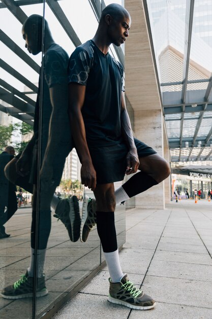 Rozważana afrykańska młoda męska atleta opiera na odbijającym lustrze przy outdoors