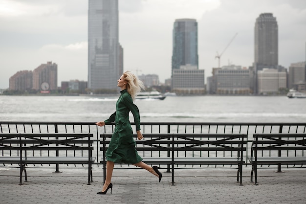 Bezpłatne zdjęcie rozważna kobieta biega w jej eleganckiej sukni wzdłuż rzecznego brzeg w nowy jork