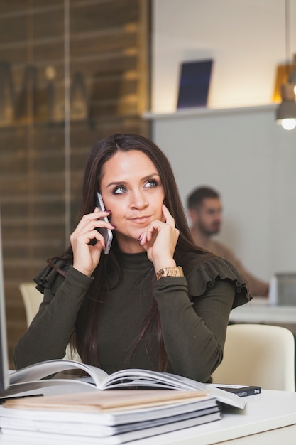 Bezpłatne zdjęcie rozważna kobieta na telefonie w biurze