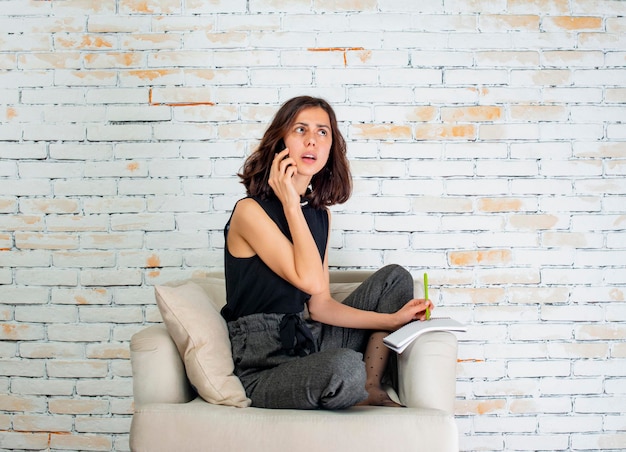 Rozważna kobieta siedzi na kanapie i rozmawia przez telefon Wysokiej jakości zdjęcie