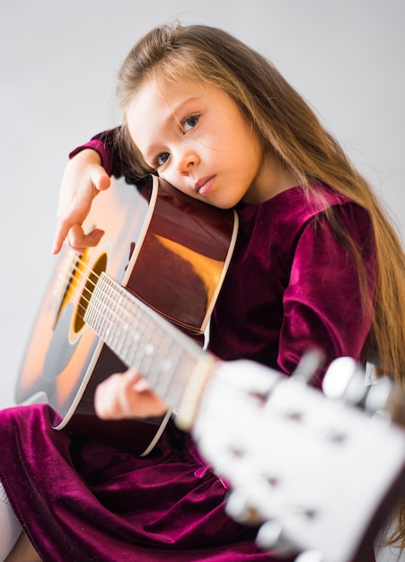 Rozważna mała dziewczynka bawić się gitarę akustyczną