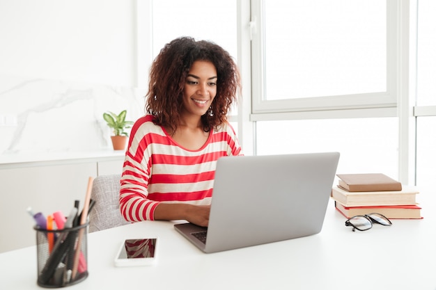 Ruchliwie kobieta w przypadkowych ubraniach pracuje na laptopie w domu