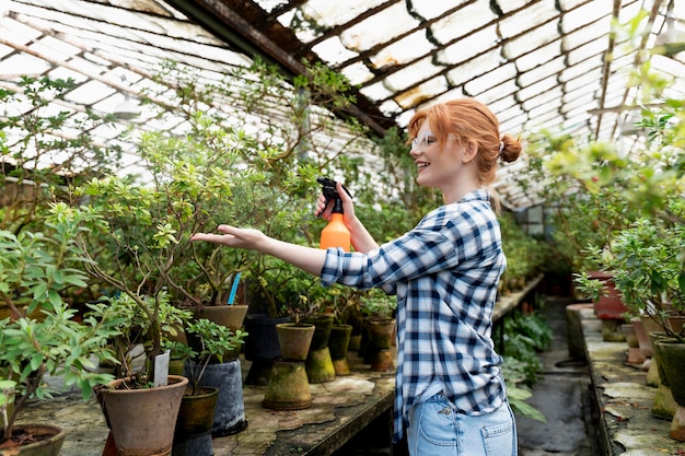 Bezpłatne zdjęcie ruda kobieta dbająca o swoje rośliny w szklarni