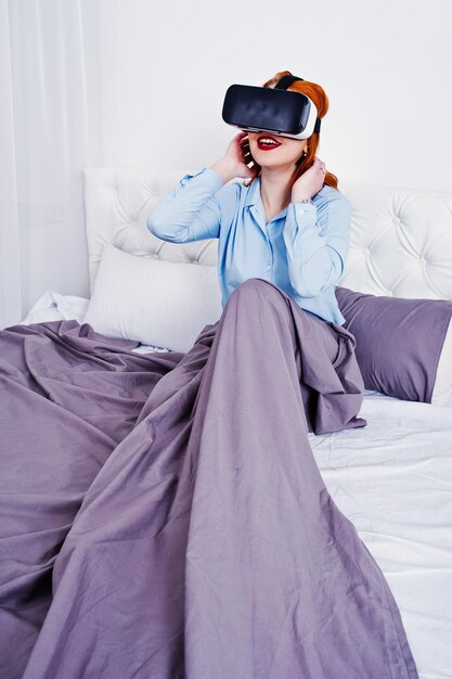 Rudowłosa dziewczyna w łóżku z okularami vr w pokoju typu studio