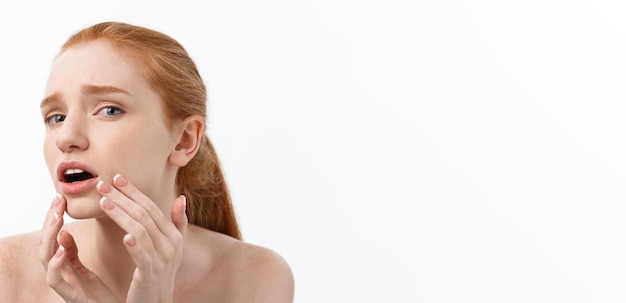Bezpłatne zdjęcie rudowłosa kobieta pokazuje palce na trądziku na twarzy