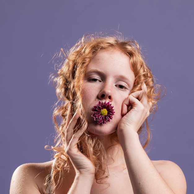 Rudzielec kobieta pozuje z chryzantemą na jej usta