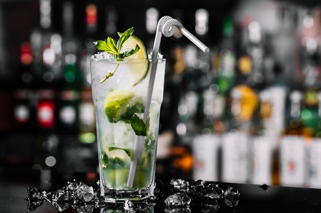 Rumowy koktajl mojito z boku z limonkową miętą i lodem w szklance