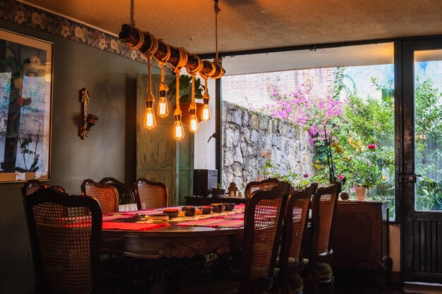 Rustykalny żyrandol wykonany z żarówek i lin nad stołem w kuchni vintage