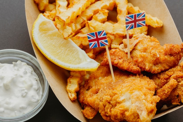 Bezpłatne zdjęcie ryba z frytkami z sosem i flagami wielkiej brytanii