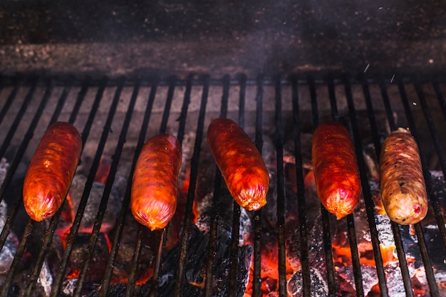 Rząd kiełbasy jest gotujący nad węglami w grillu